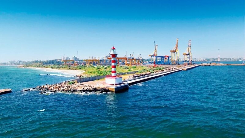 Маяк врізається в море. На другому плані видно крани й порт