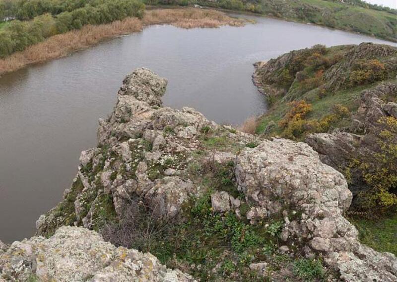 Скеля на узбережжі висить над річкою. Видно обидва береги