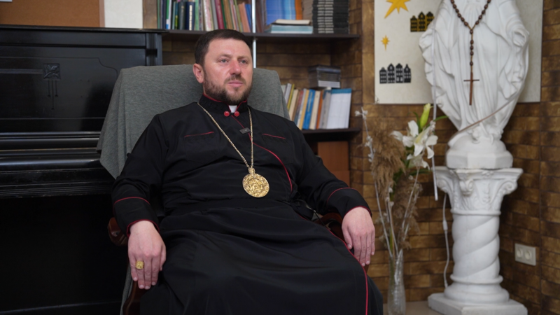 Кардинал Микола Бичок сидить у кріслі в кабінеті. За спиною фортепіано й релігійна статуя
