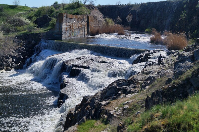 Серед каміння тече річка, в одному місці утворюється невеличкий водоспад