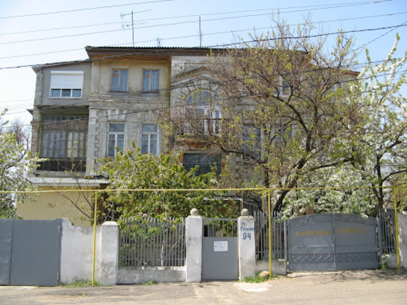 Сучасний триповерховий будинок за пошарпаним біло-сірим парканом