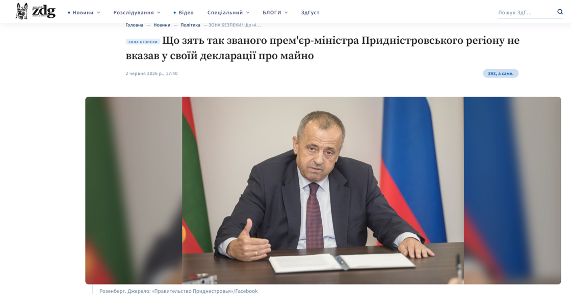 За столом сидить чиновник, перед ним відкрита папка. Він щось розповідає журналістам