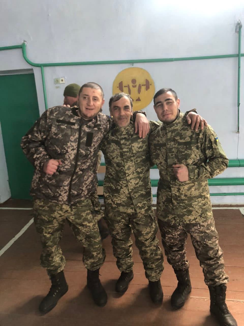 Три чоловіки у військовій формі стоять обійнявшись