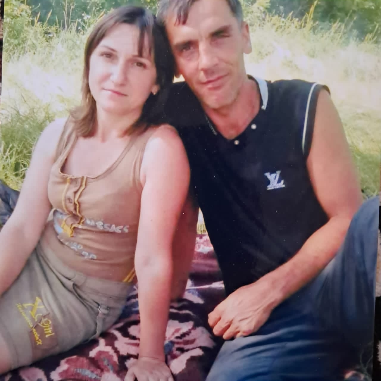 Чоловік і жінка сидять на простирадлі на траві