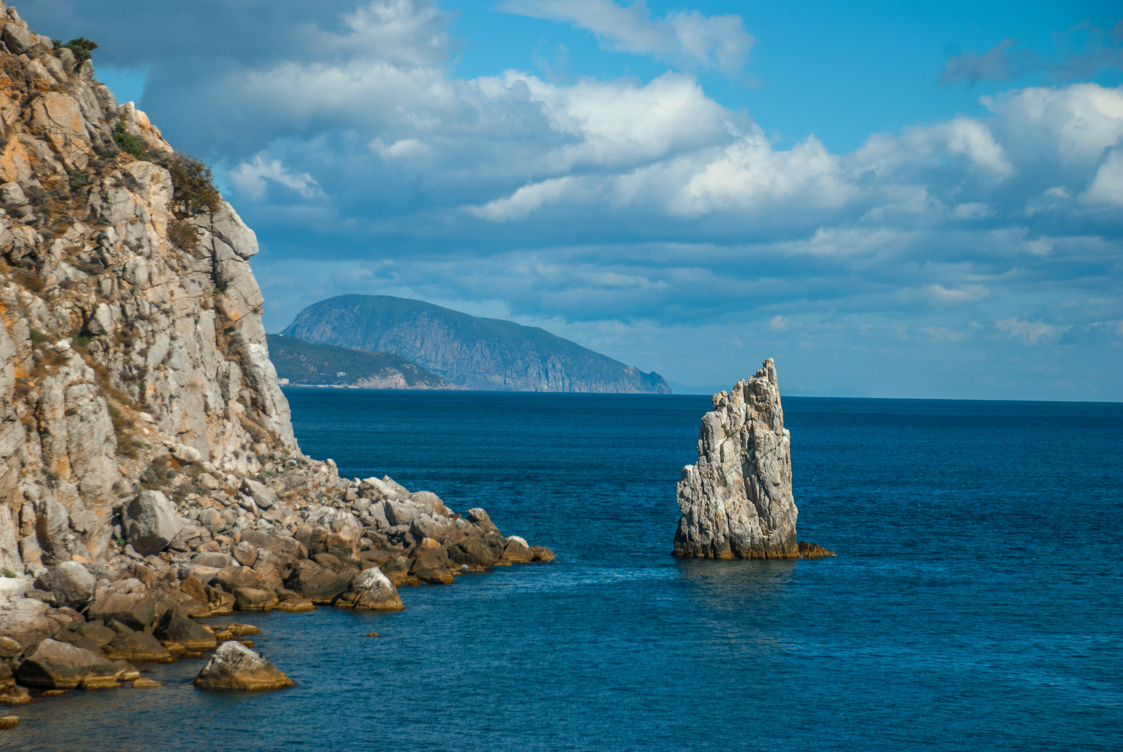 Скеля в морі біля високої гори