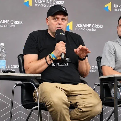 Чоловік сидить і щось розповідає на форумі